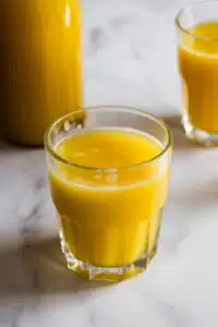 Orange lemonade in glass with citrus slices and mint